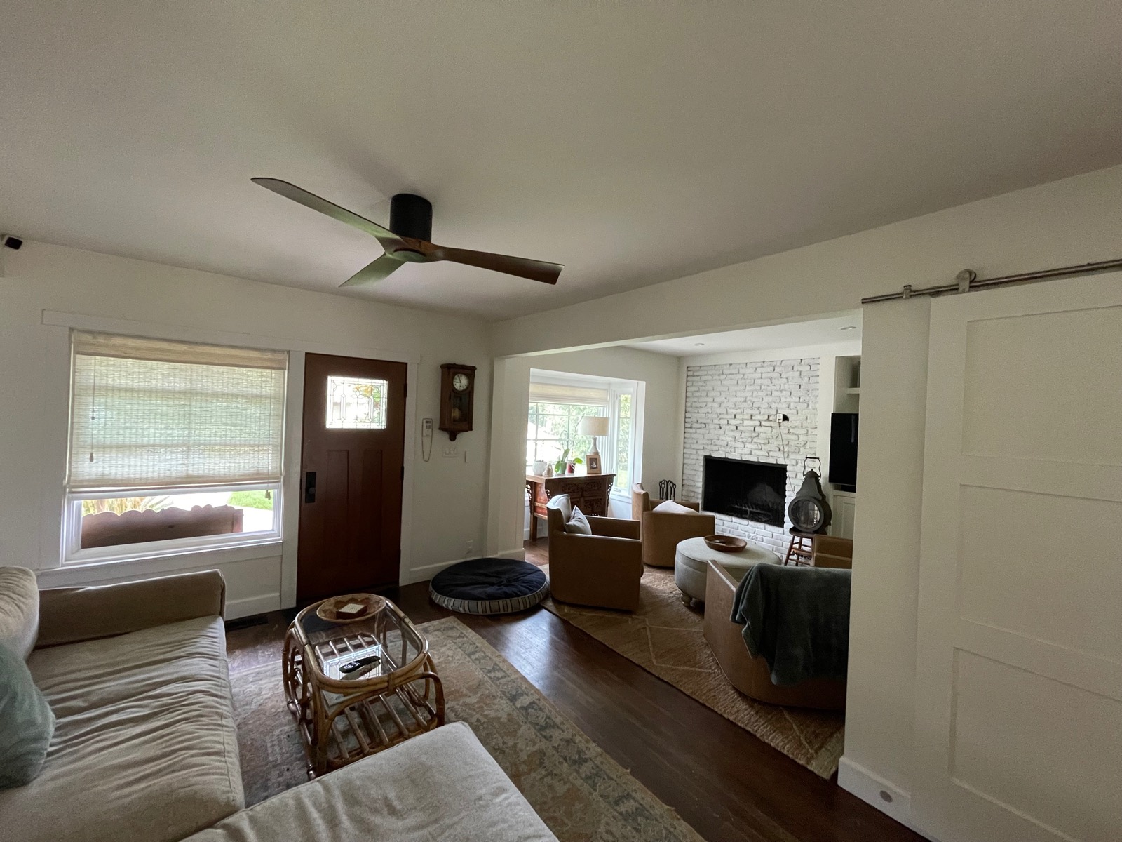 Two-tone ceiling fan installed in a living room, with a brick fireplace in the next room past a sliding barn door